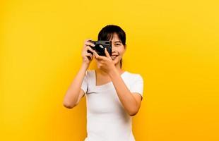 Photographer girl taking pictures. Isolated model on yellow background. with copy space photo