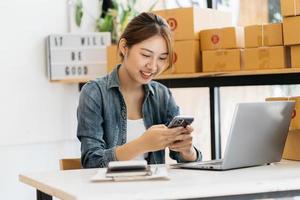 Starting Small business entrepreneur SME freelance,Portrait young woman working at home office, BOX,smartphone,laptop, online, marketing, packaging, delivery, SME, e-commerce concept photo