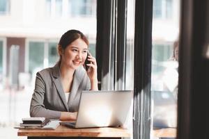 Protrait of Beautiful businesswoman sitting at desk and working with laptop computer and smartphone. photo