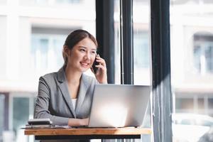 Protrait of Beautiful businesswoman sitting at desk and working with laptop computer and smartphone. photo