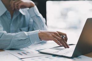 Businessman hand pressing on the laptop keyboard, World of technology and internet communication, Financial professionals use laptop to calculate and check real estate earnings. photo