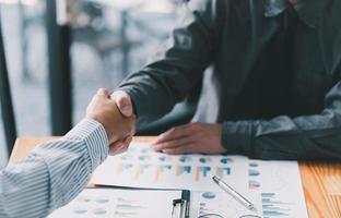 businesspeople are shaking their hands after signing a contract, while standing together in a sunny modern office, close-up. Business communication, handshake, and marketing concept photo