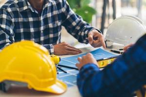 reunión de trabajo en equipo de ingenieros, trabajo de dibujo en la reunión de planos para el trabajo del proyecto con un socio en la construcción de modelos y herramientas de ingeniería en el concepto de sitio de trabajo, construcción y estructura. foto