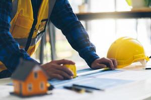 arquitecto o ingeniero que trabaja en la oficina con planos, inspección de ingenieros en el lugar de trabajo para el plan arquitectónico, esbozo de un proyecto de construcción, concepto de construcción empresarial. foto