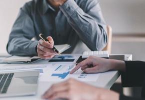 Two colleagues discussing data with document data on desk table. Close up business people meeting to discuss the situation on the market. photo