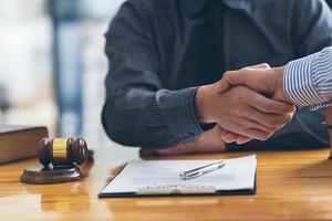 Handshake after good cooperation, Businesswoman Shaking hands with Professional male lawyer after discussing good deal of contract in courtroom, Concepts of law, Judge gavel with scales of justice. photo