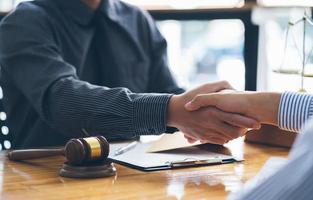 Businessmen shaking hands above the wooden desk in a modern office, close up. Unknown business people at meeting. Teamwork, partnership and handshake concept. photo