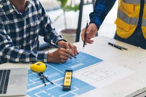 reunión de ingenieros y arquitectos trabajando y señalando dibujos en la oficina para discutir. herramientas de ingeniería y concepto de construcción, ingenieros y arquitectos hacen una lluvia de ideas. foto