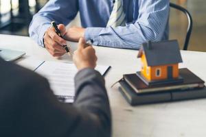 la casa de bienes raíces apunta a la firma del contrato de seguro y se lo explica a los clientes en la oficina. concepto de agencia de la casa. foto