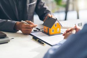 modelo de casa con el agente y el cliente discutiendo el contrato para comprar, obtener un seguro o un préstamo de bienes raíces o propiedades. foto