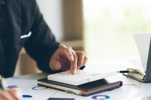 Close up Businessman using calculator and laptop for calaulating finance, tax, accounting, statistics and analytic research concept photo