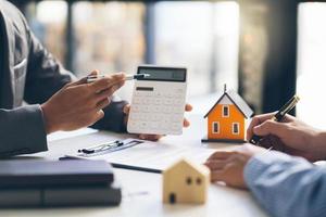 modelo de casa con el agente y el cliente discutiendo el contrato para comprar, obtener un seguro o un préstamo de bienes raíces o propiedades. foto