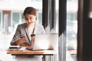 Protrait of Beautiful businesswoman sitting at desk and working with laptop computer and smartphone. photo