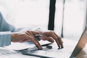 Businessman hand pressing on the laptop keyboard, World of technology and internet communication, Financial professionals use laptop to calculate and check real estate earnings. photo