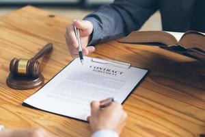 Business people negotiating a contract. Human hands working with documents at desk and signing contract, lawyer concept. photo