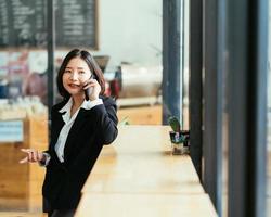 Portrait of a smiling Asian businesswoman talking on a phone in the cafe during the break from a meeting. photo