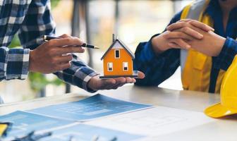 Architect and engineer meeting Planning for a New Project with construction equipment on table, Architect and engineer working with blueprint and house model. photo