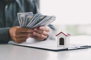 Male real estate agent hands counting money after successful deal for buying house. photo