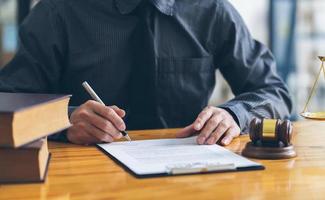 negocios y abogados discutiendo documentos contractuales con escala de latón en el escritorio de la oficina. derecho, servicios legales, asesoramiento, justicia y concepto de derecho. foto