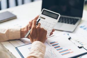 Close up hand of stress young asian businessman,male is pressing a calculator to calculate tax income and expenses, bills, credit card for payment or payday at home, office.Financial, finance concept. photo