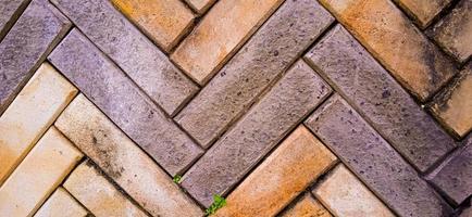 amarillo y naranja zig zag fondo de baldosas de ladrillo con algo de musgo verde y marrón crece en las superficies de ladrillo. disponible para texto. adecuado para la construcción, la arquitectura, la inspiración para la decoración del hogar foto