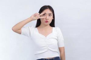 mujer asiática con cabello largo usa camisa blanca y muestra una actuación divertida sobre fondo blanco. foto