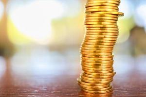 Business, Money, Finance, Security and Saving Concept. Close up of stack of gold coins on wooden table under sunlight with copy space. photo
