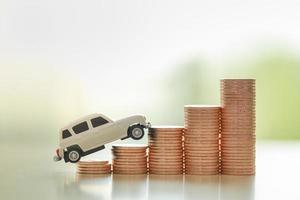Automobile Business Finance Concept. Close up of white miniature car toy on stack of coins with copy space. photo