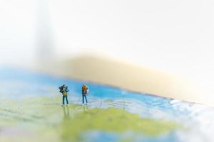 Travelling concepts. Two of miniature man and woman miniature figures with backpack standing on world map with copy space. photo