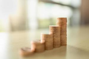 Business, Money, Finance, Security and Saving Concept. Close up of stack of coins on wooden table under sunlight with copy space. photo