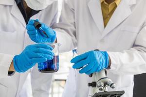Close up of two professional doctor scientist using dropper to test and research in working laboratory with microscope. photo