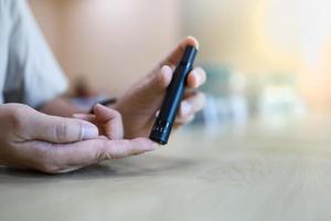 Close up of man hands using lancet on finger to check blood sugar level by Glucose meter. Use as Medicine, diabetes, glycemia, health care and people concept. photo