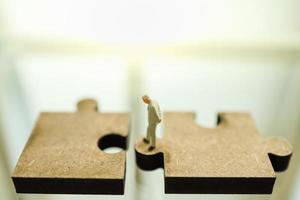 Business, Teamwork, Planning and Work Concept. Close up of businessman miniature figure people standing and looking to gab between two wooden jigsaw piece with copy space. photo