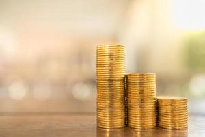 Business, Money, Finance, Security and Saving Concept. Close up of three stack of gold coins on wooden table under sunlight with copy space. photo