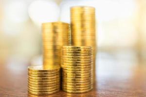 Business, Money, Finance, Security and Saving Concept. Close up of stack of gold coins on wooden table under sunlight with copy space. photo