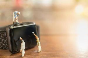 Technology, Time Concept. Close up of group of worker and painter miniature figure people clean and paint on smart watch on wooden table and copy space. photo