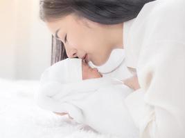 una hermosa mujer asiática llevó a su bebé recién nacido y besó con felicidad foto