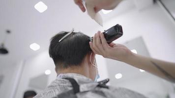 Cabeleireiro profissional em câmera lenta cortando cabelo com máquina de cortar cabelo, vista traseira lateral da cabeça masculina sentada no barbeiro moderno, close-up cinematográfico de uma loja de cabeleireiro dando corte de cabelo desbotado, máquina de cortar cabelo6 video