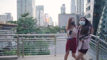 Zwei asiatische Geschäftsfrauen, die die Hand halten, laufen auf der Stadtüberführung, weil sie zu spät zum Geschäftstermin kommen, neue normale Jobsuche, Risiko, während einer Pandemie nach draußen zu gehen, Freunde trus video