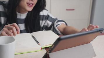jeune fille asiatique étudiant le cours d'apprentissage en ligne en ligne, l'enseignement à domicile écrivant sur un cahier, se concentrant sur les devoirs, les cours à distance, l'école à domicile, le travail à domicile pendant le verrouillage video