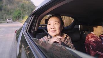 cabelos pretos idosos asiáticos sentados no banco de trás do carro e olhando pela janela em uma unidade lenta, mais velhos no transporte, um membro importante da família desfruta de uma vista lateral natural, felicidade de ficar juntos