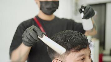 barbiere maschio asiatico, l'uomo con la maschera nera si fa tagliare i capelli. opportunità di lavoro barbiere. capelli a pettine spray d'acqua, attività di barbiere durante il virus corona covid-19 riaprire l'attività dopo l'anti-quarantena pandemica video
