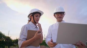 um pequeno grupo de engenheiros conversando e treinando trabalhando usando planta e tablet portátil juntos na área do canteiro de obras, um capataz ensinando estagiário, diversidade de pessoas, conceito de indústria da construção video