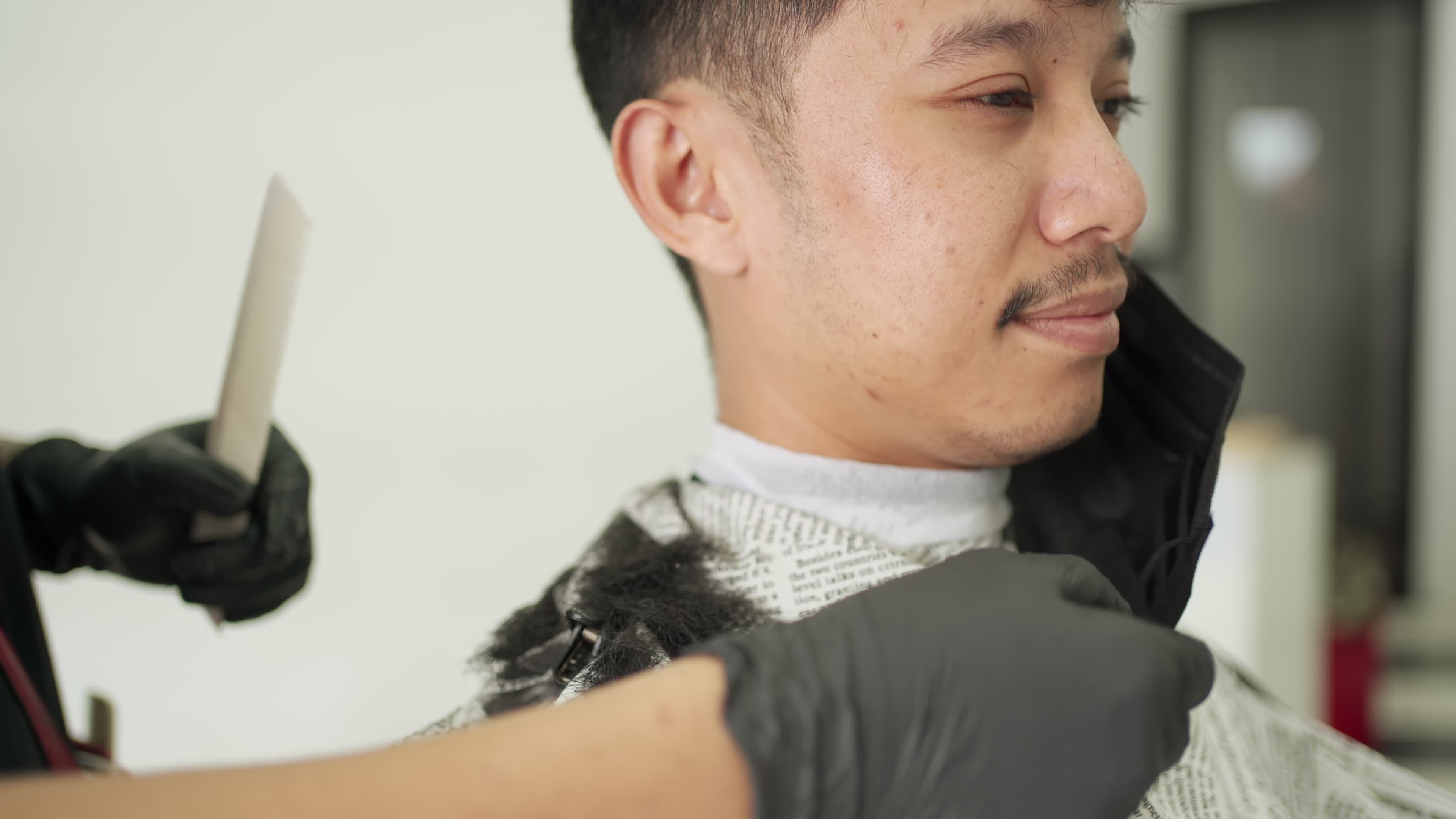Barber remove customer mask then use scissor to trim his sideburns