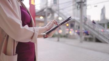 Close up shot of business woman working with digital tablet touch on the screen, device application sensitive touching mechanism, multitasking lady working online standing outside the office building video