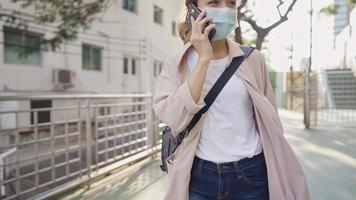 Portrait of active young worker talks on phone while walking on the overpass walking way in public green park, technology wireless and modern living, new normal lifestyle and stay isolated,