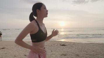 Young active asian girl running on the beach with sunset on the background, morning exercise to start the day, refresh moment at the island shore, self empower sport motivation training, fit girl video