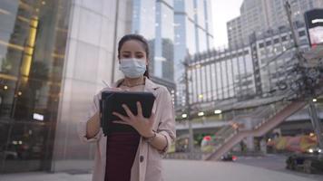 portrait d'une belle femme d'affaires asiatique en smart casual utilisant une tablette numérique et un stylo sans fil à l'extérieur d'un immeuble de bureaux, création et vente d'actifs numériques, activité de commerce électronique, technologie de commodité video