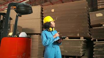 uniforme de segurança trabalhadora afro-americana e capacete inspecionam armazenamento, pedido de estoque de armazém de fábrica, pilhas de empilhamento de fabricação de papelão, gerenciamento de produtos da indústria para transporte logístico. video