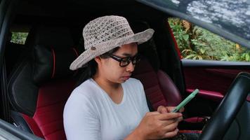Asian female traveler uses a GPS navigation map on her smartphone while sitting in a car. Tourists travel in the forest on vacation by car. video